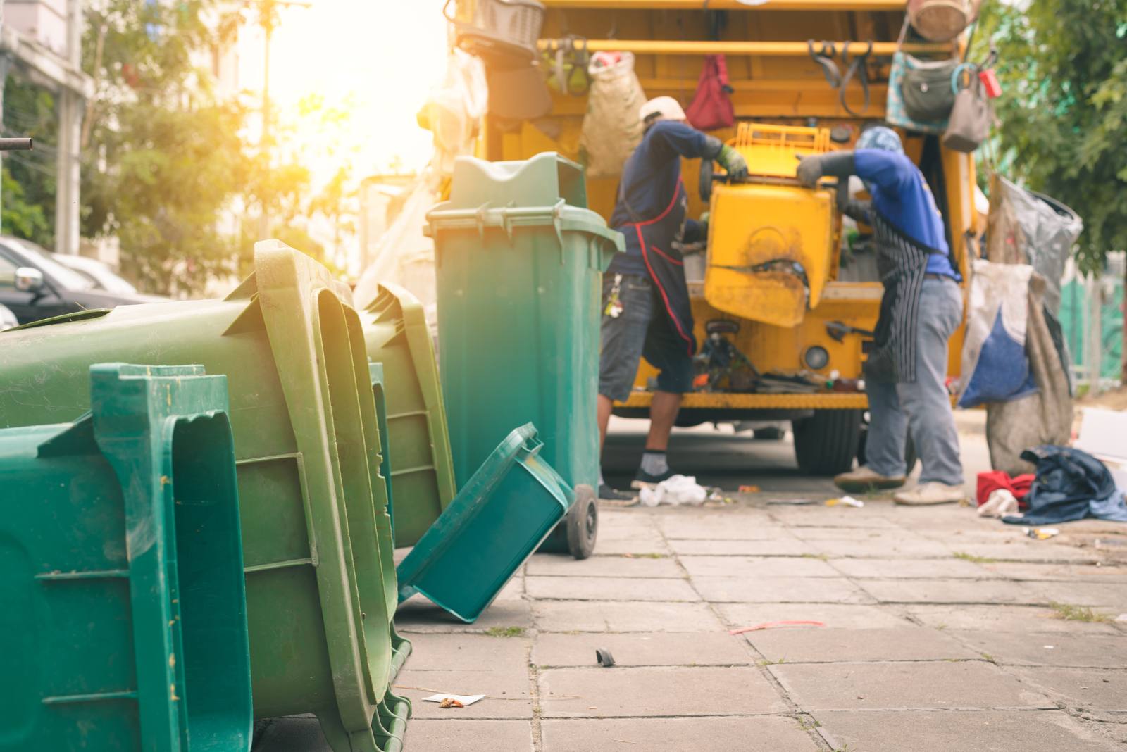 A refuse collection crew emptying wheelie bins on a street